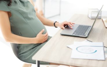 Сотрудница работает с документами за ноутбуком