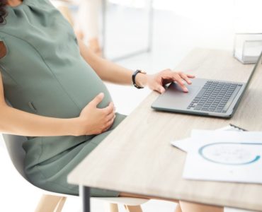 Сотрудница работает с документами за ноутбуком
